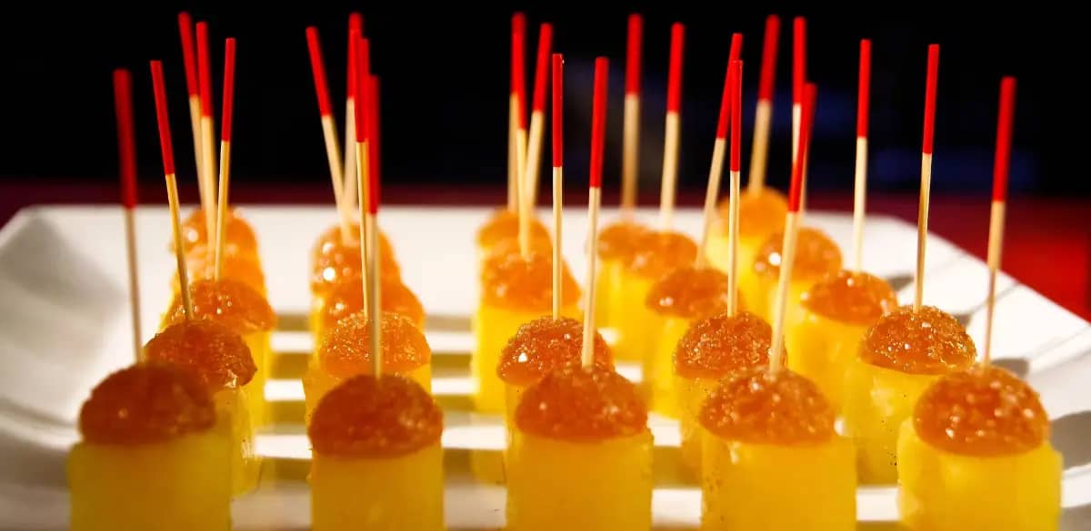 Bunte, gelatineähnliche Leckereien auf einem Teller mit roten Sticks.