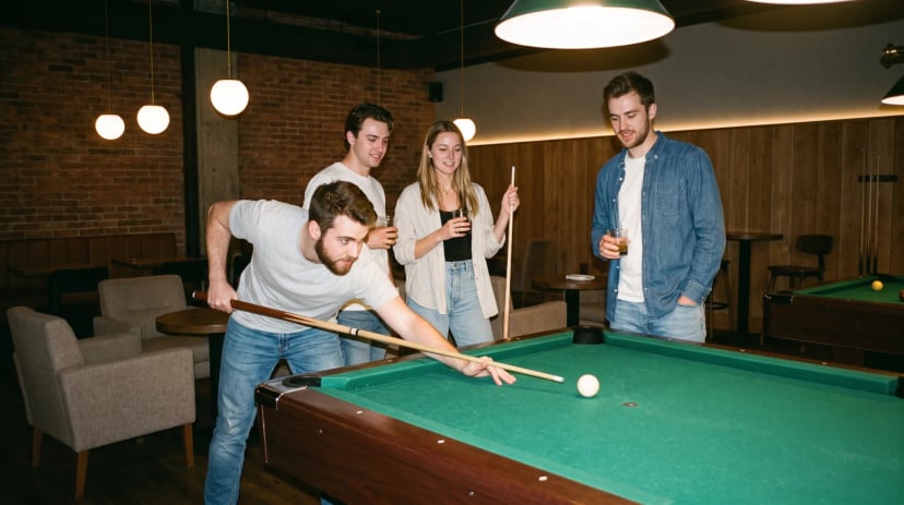 Freundesgruppe spielt Poolbillard in einem stilvollen Billardsalon, einer stößt