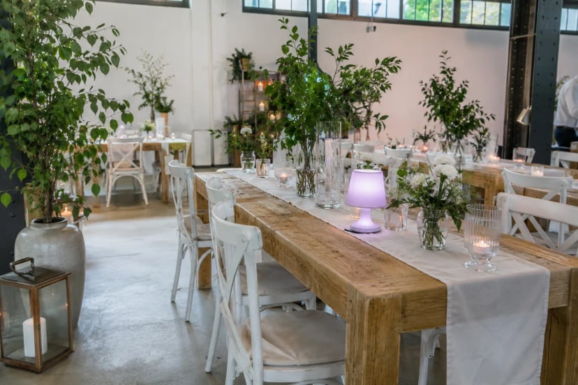 Eventausstattung in einem hellen Loft in Much mit langer Holztafel, weißen Stühlen und Kerzendekoration