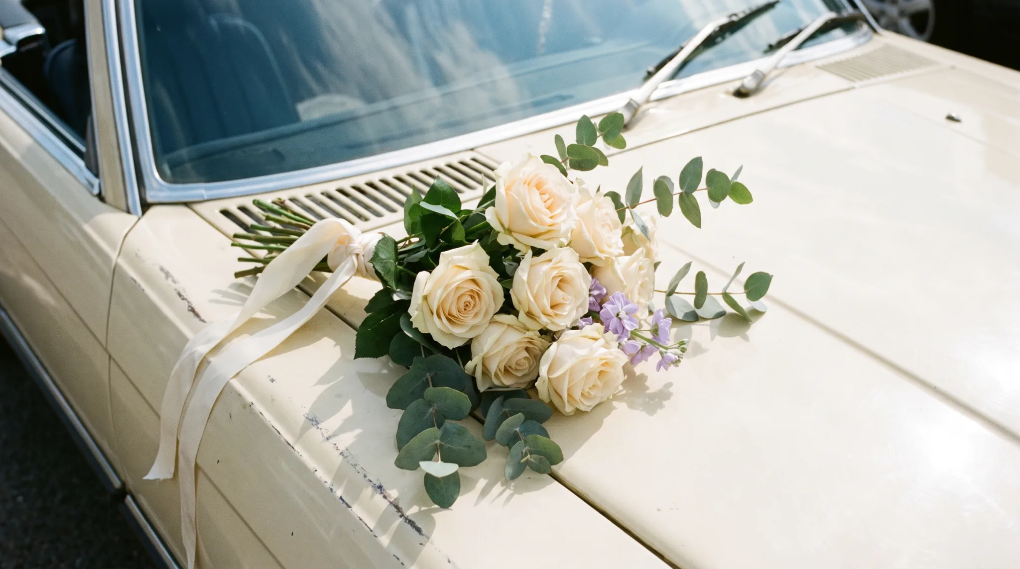 Nahaufnahme des Blumenschmucks auf der Motorhaube eines hellen Hochzeitsautos in Bonn