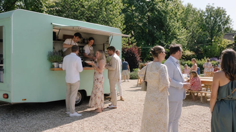 Gäste holen sich Essen an einem logofreien Foodtruck bei einem Sommerfest, Beispiel für Foodtruck-Catering