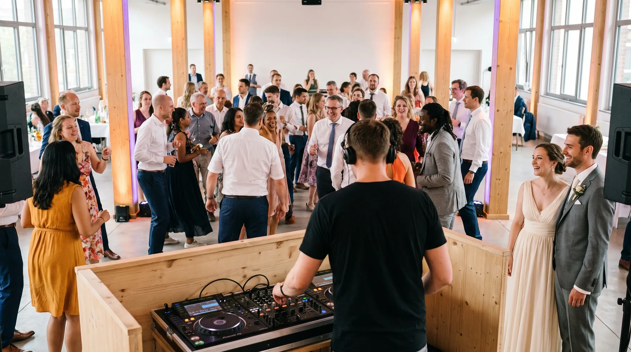 Hochzeits-DJ Köln: DJ mit Kopfhörern an professionellem Mischpult, warmes Bernstein- und Violettlicht.