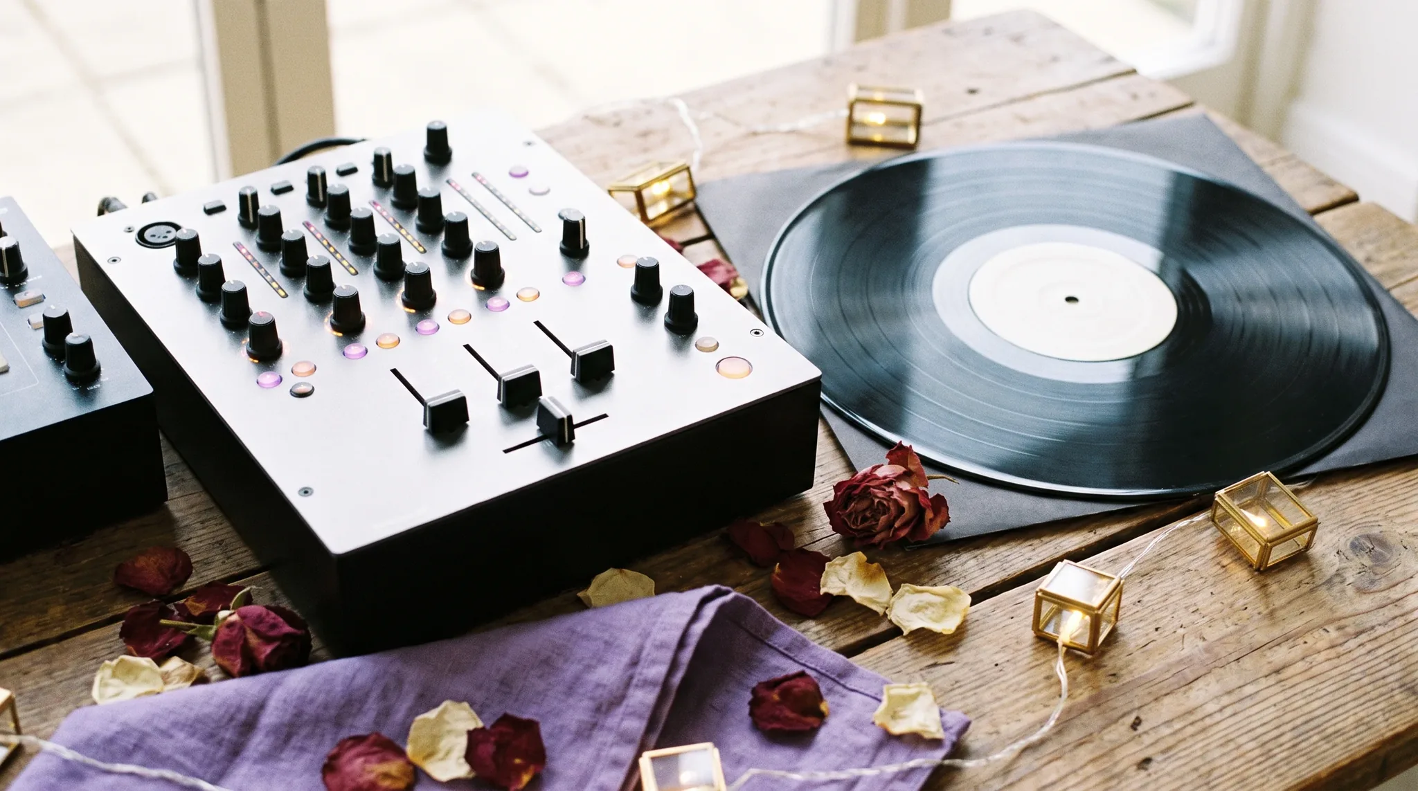 Hochzeits-DJ in Pulheim: Mixer, Schallplatten, Kopfhörer und Kabel auf dunklem Holz, flankiert von Teelichtkerzen und einem Zweig getrockneten Eukalyptus.