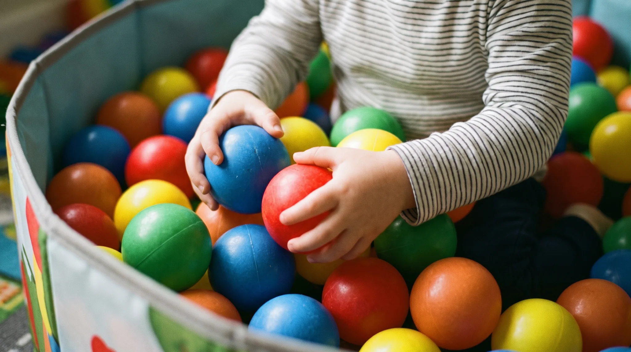 Kinderhände greifen bunte Bälle in einem Bällebad