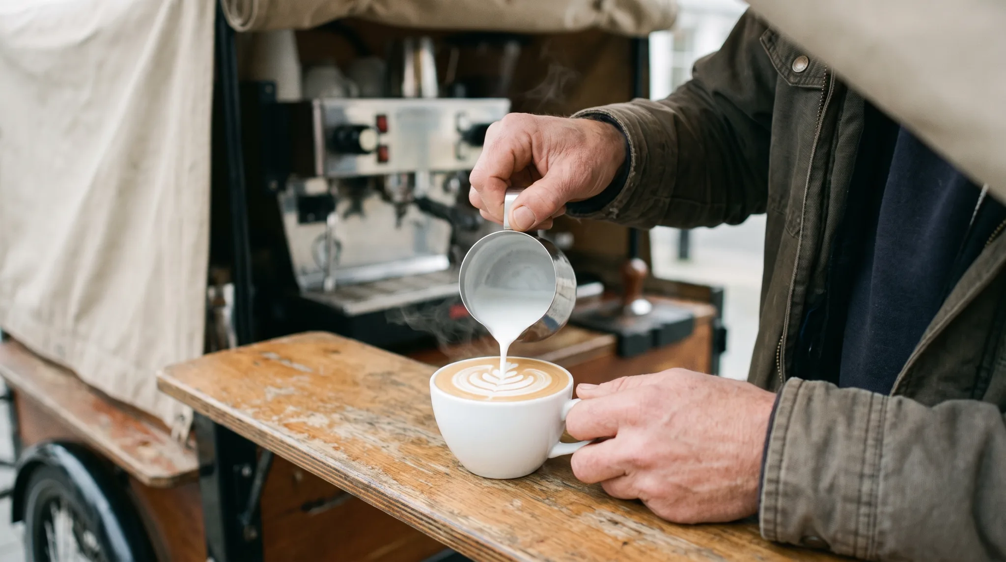 Barista gießt Latte Art in eine Tasse an einem mobilen Kaffeebike