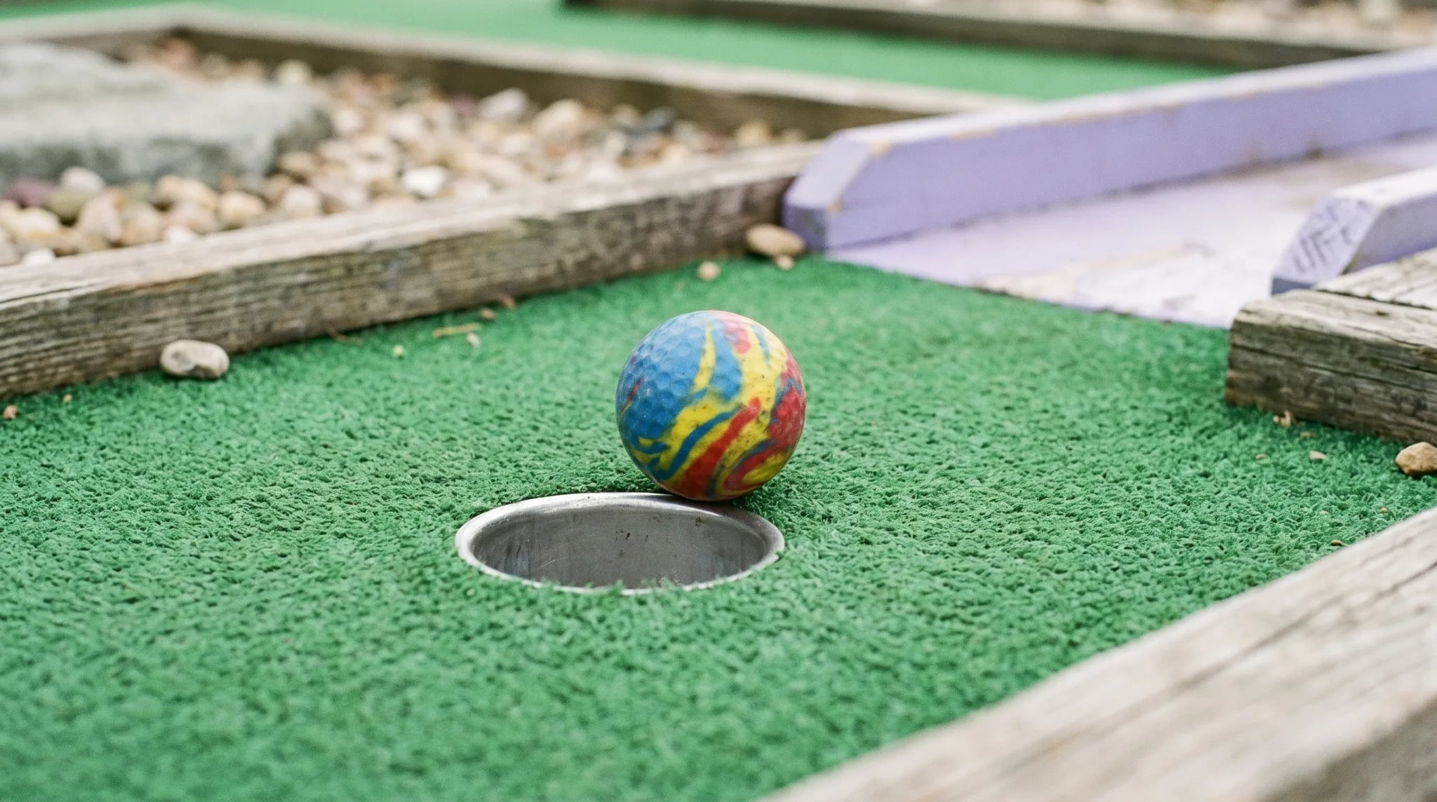 Bunter Minigolfball rollt am Loch vorbei auf einer Minigolfanlage in Köln