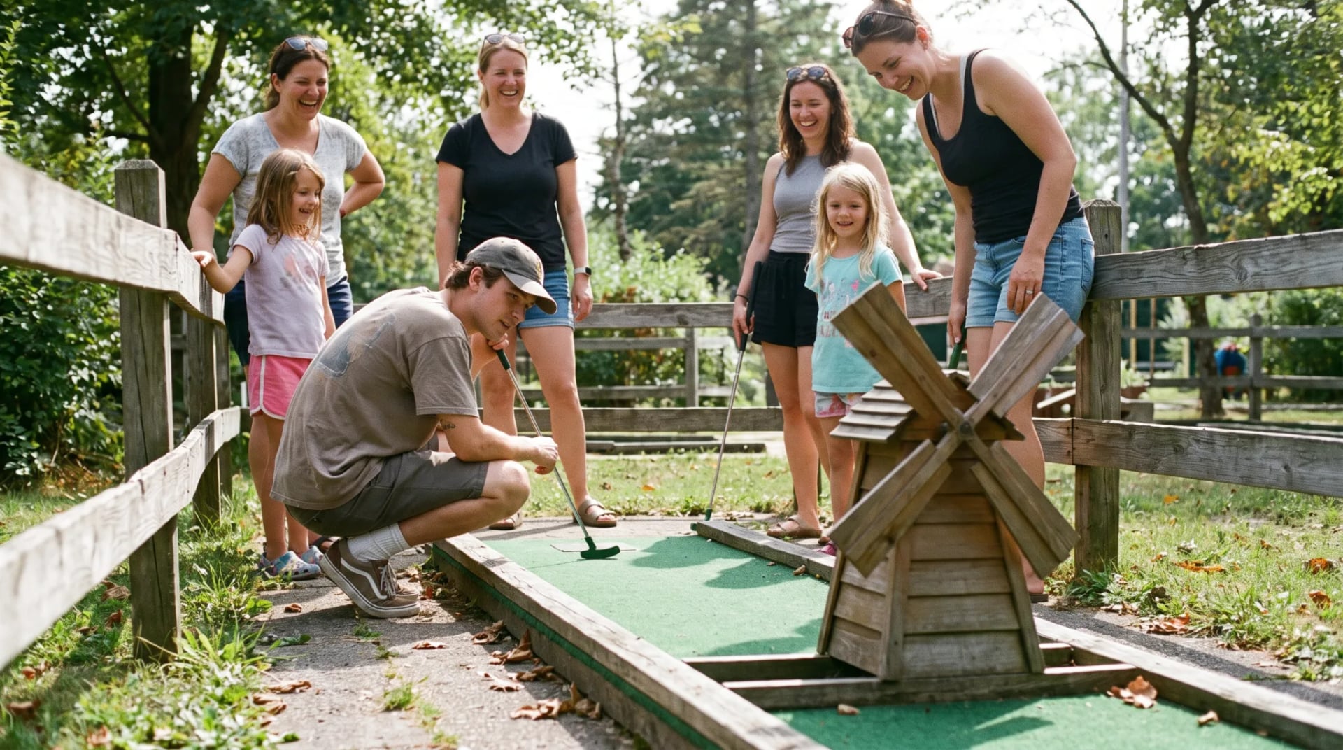Familie und Freunde spielen gemeinsam Minigolf auf einer Outdoor-Anlage