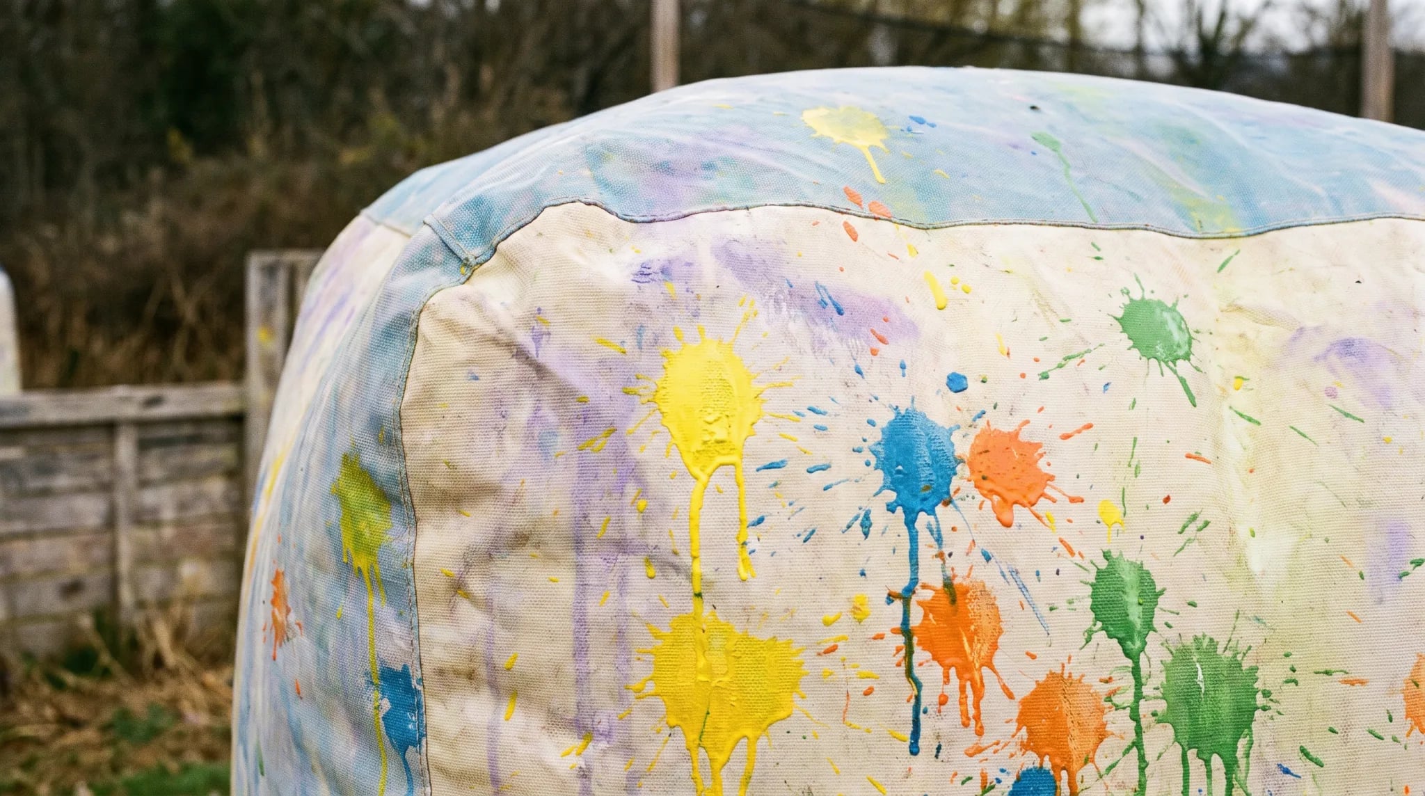 Paintball-Maske und Markierer mit bunten Farbklecksen auf einer Holzbank in Bonn