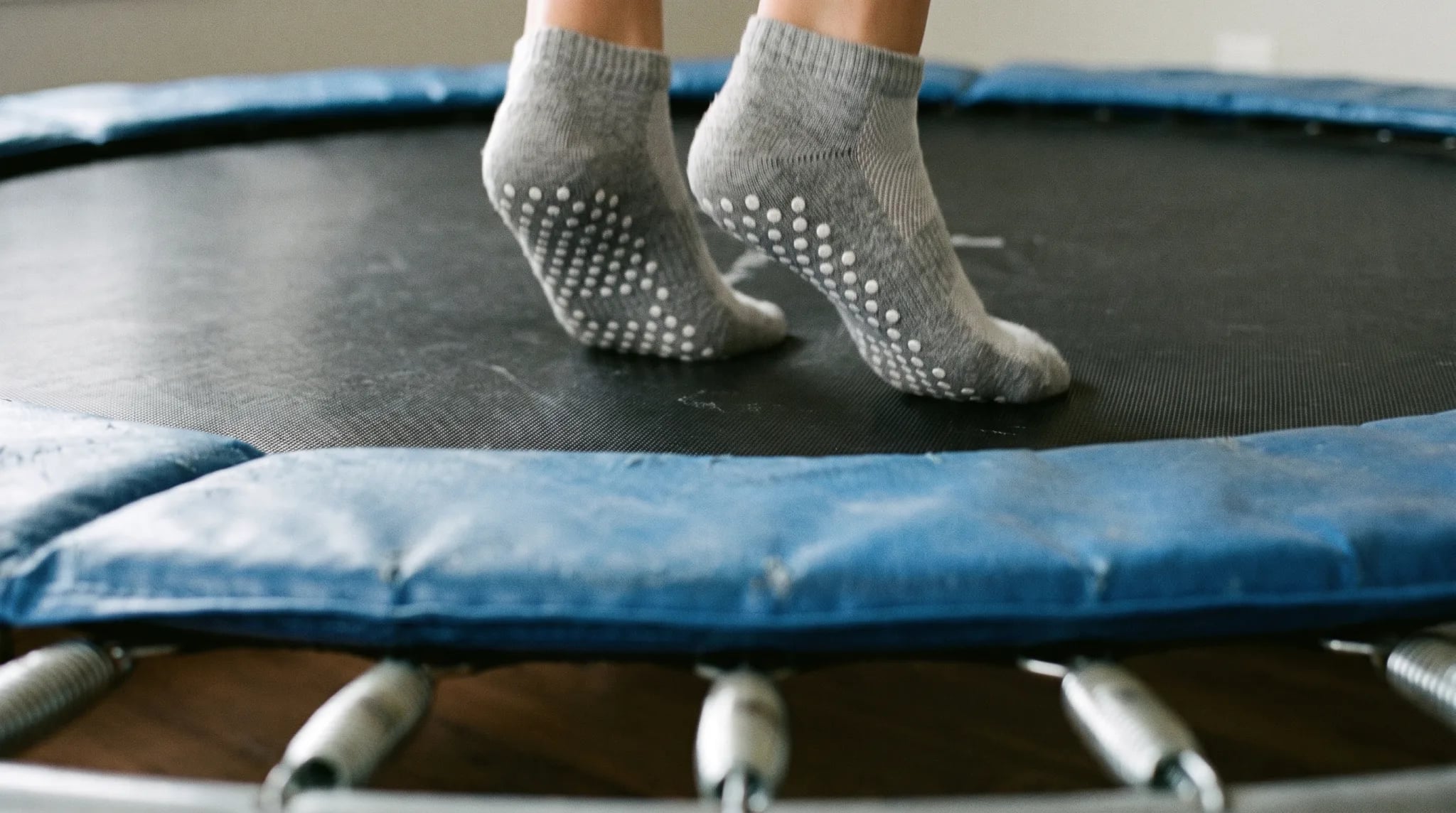 Füße in Stoppersocken auf der Sprungfläche eines Trampolins